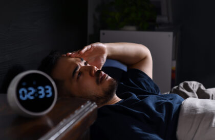 Depressed young Asian man lying in bed cannot sleep from insomnia