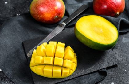 Tropical ripe mango fruit. Black background. Top view.