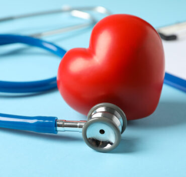 Stethoscope and heart on blue background, close up